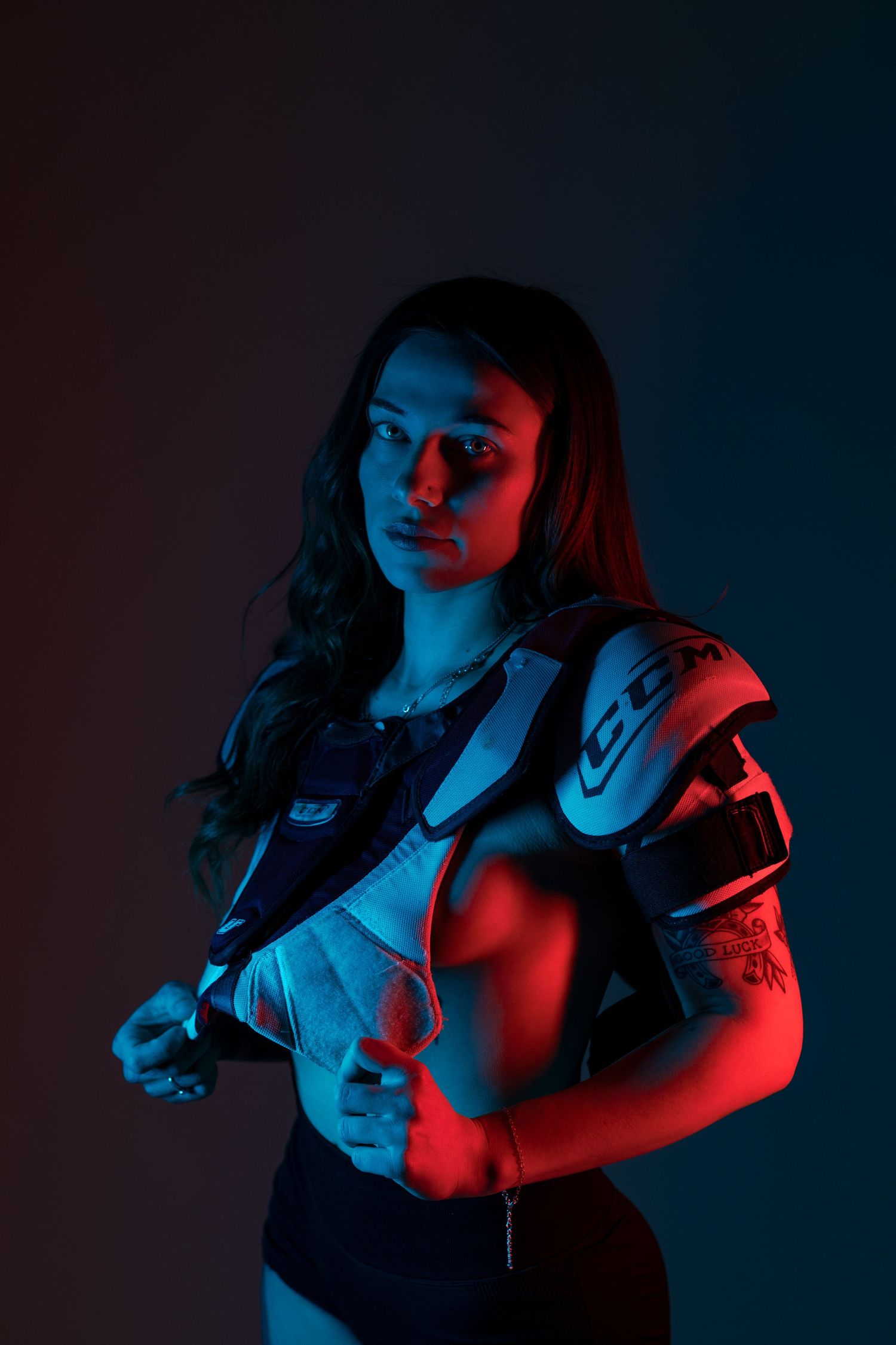 Dramatic portrait with red and blue lighting shows a figure in athletic gear against dark background.