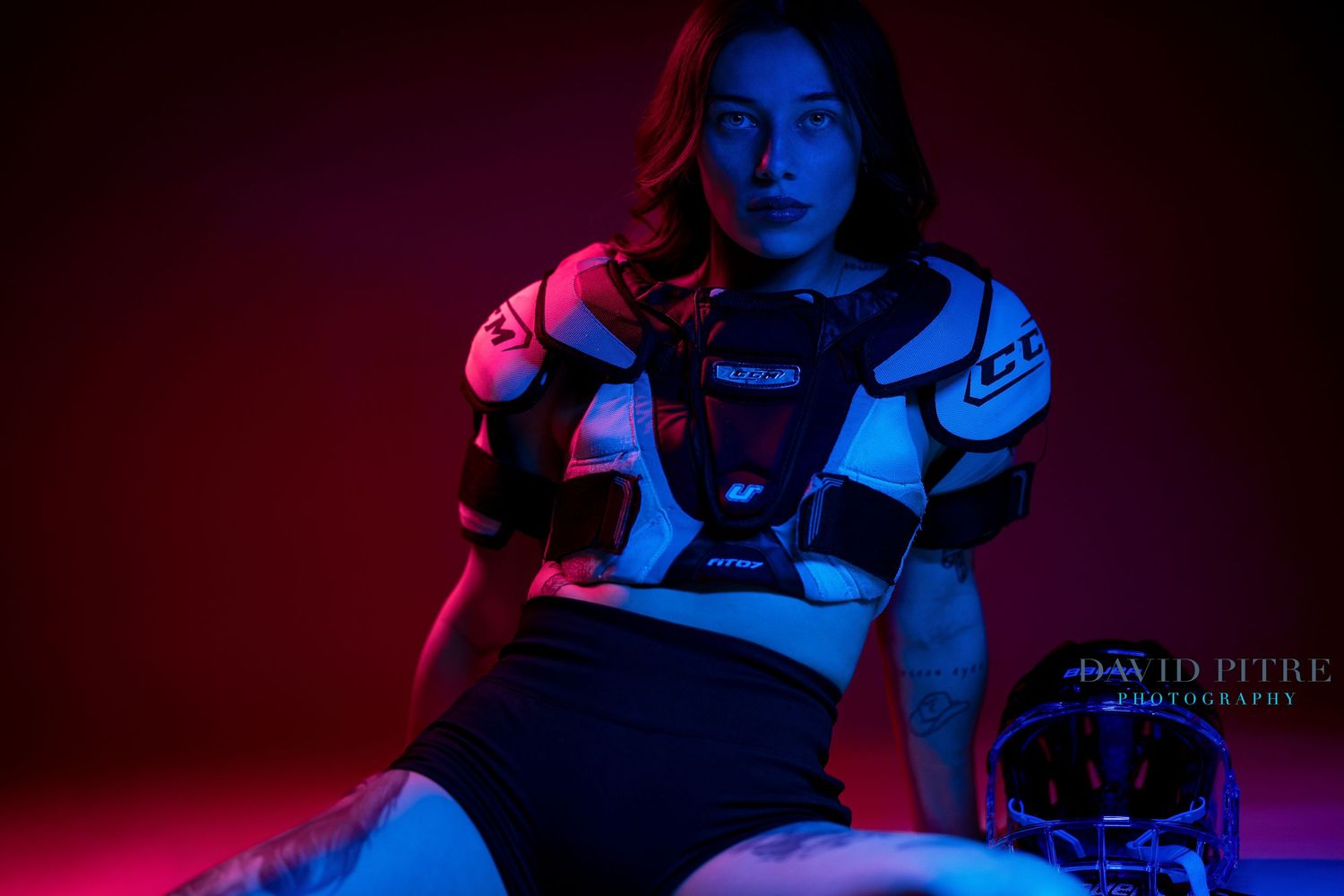 Dramatic portrait with blue and red lighting creating moody contrast against dark background.
