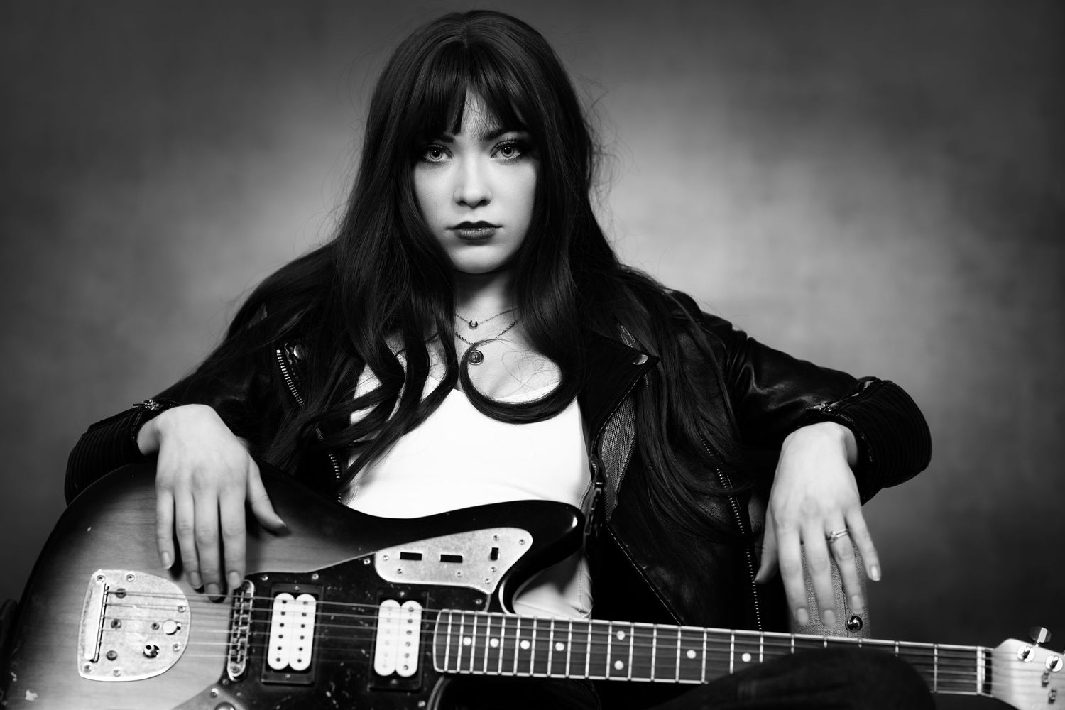 Black and white collage of six photos showing someone playing an acoustic guitar and electric guitar against dark background.