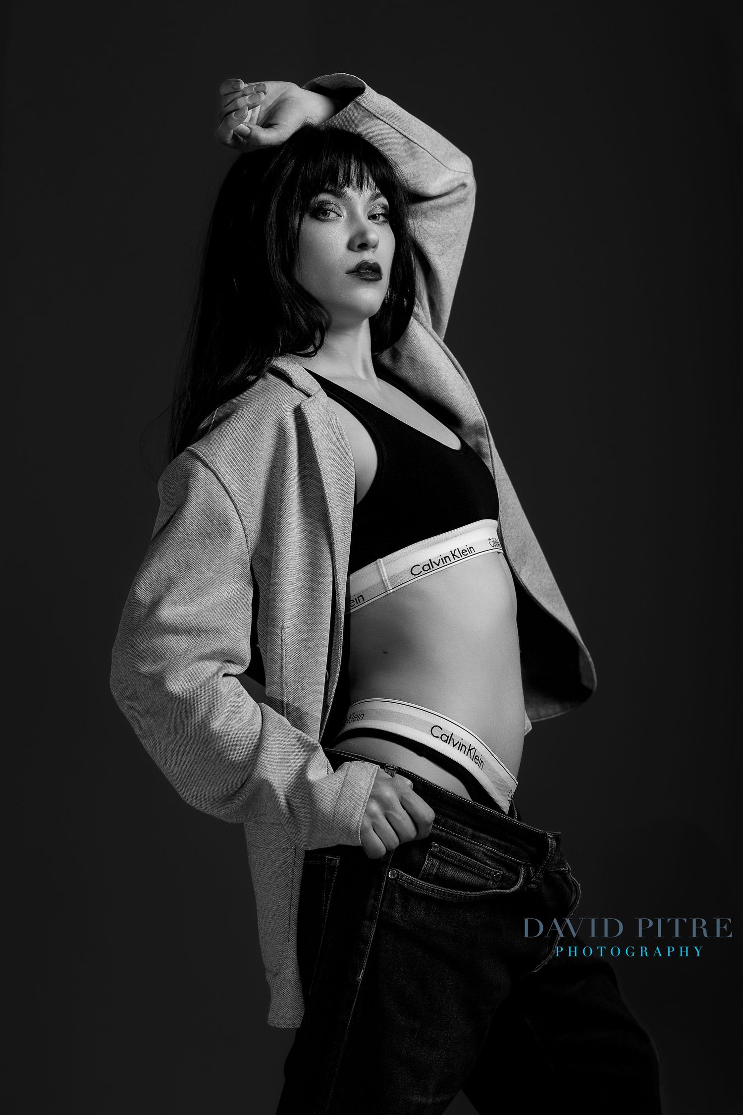 Black and white portrait showcasing Calvin Klein sportswear with gray hoodie and denim styling.