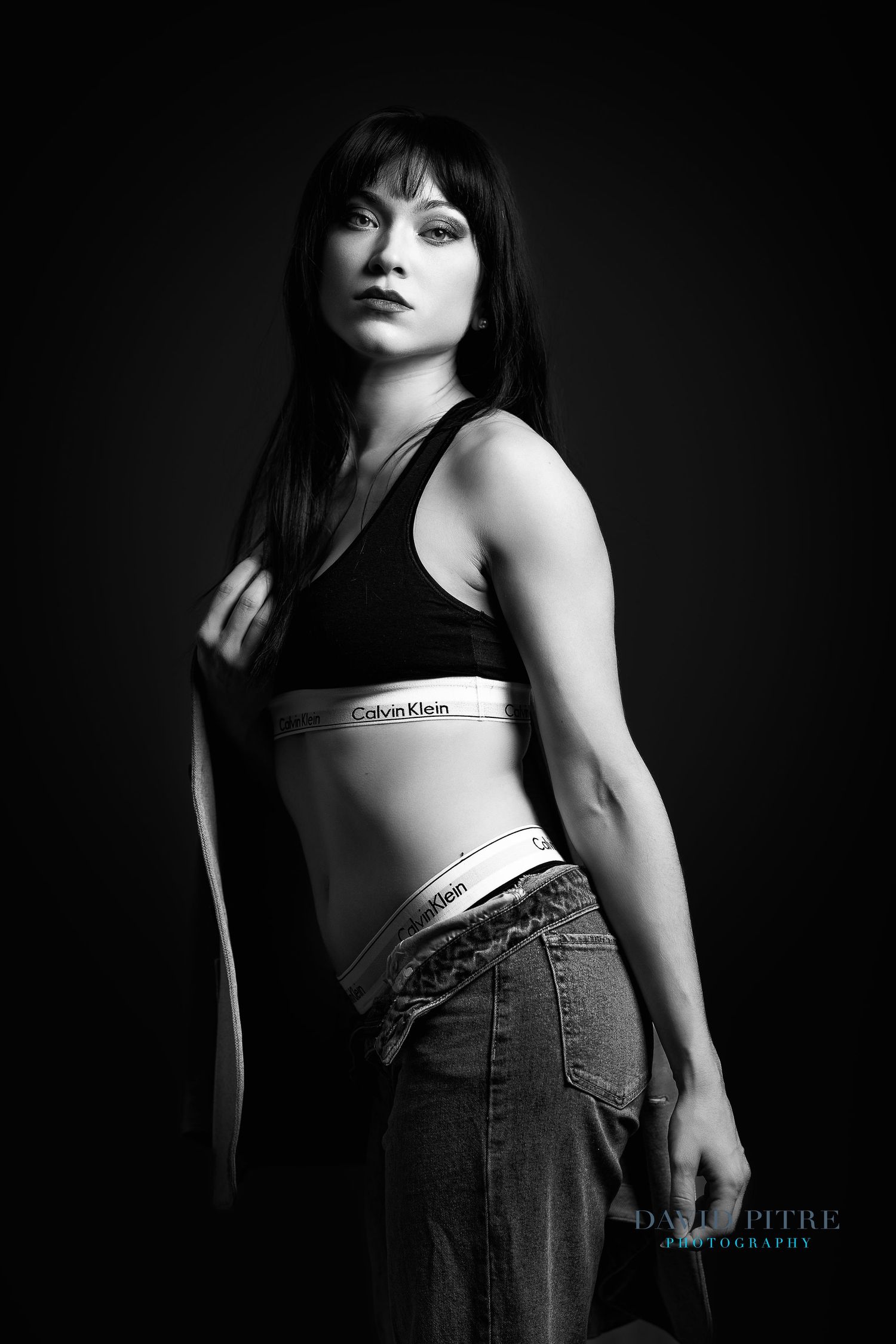 Black and white fashion portraits showing a model in Calvin Klein top and denim in dramatic lighting.