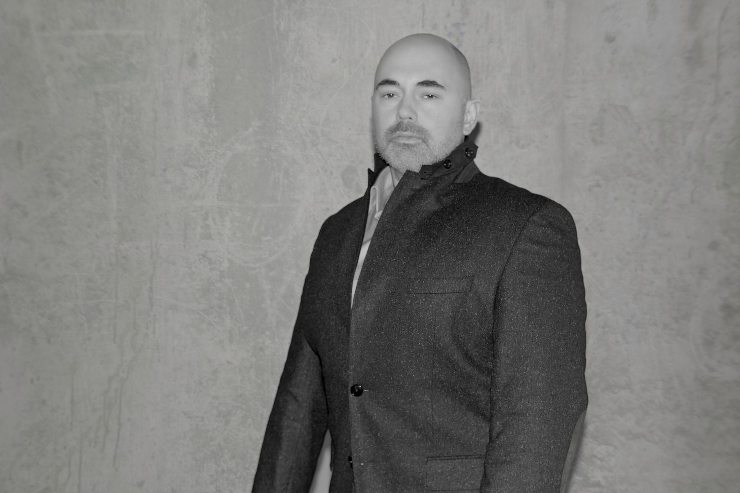 Professional headshot portrait in black and white against a textured gray background.