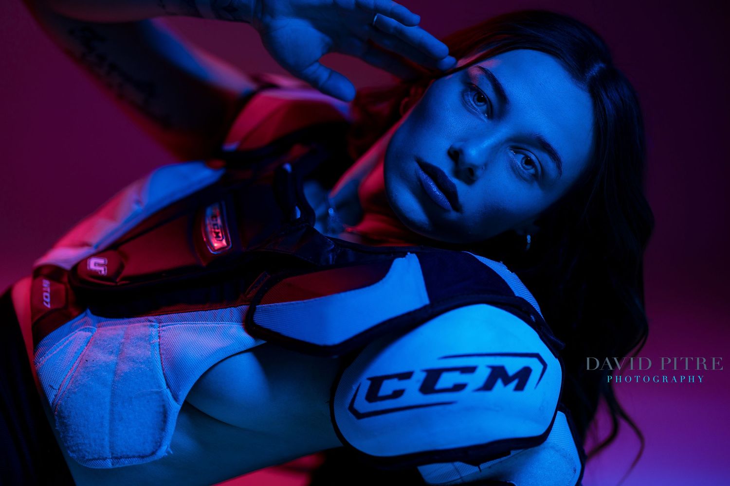 Sports-themed portrait featuring CCM hockey gear illuminated by vibrant blue and red lighting.