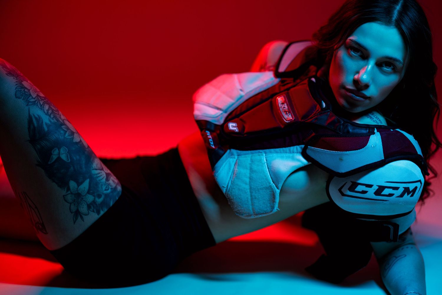 Hockey goalie equipment and protective gear laid out on red background with dramatic lighting and shadows.