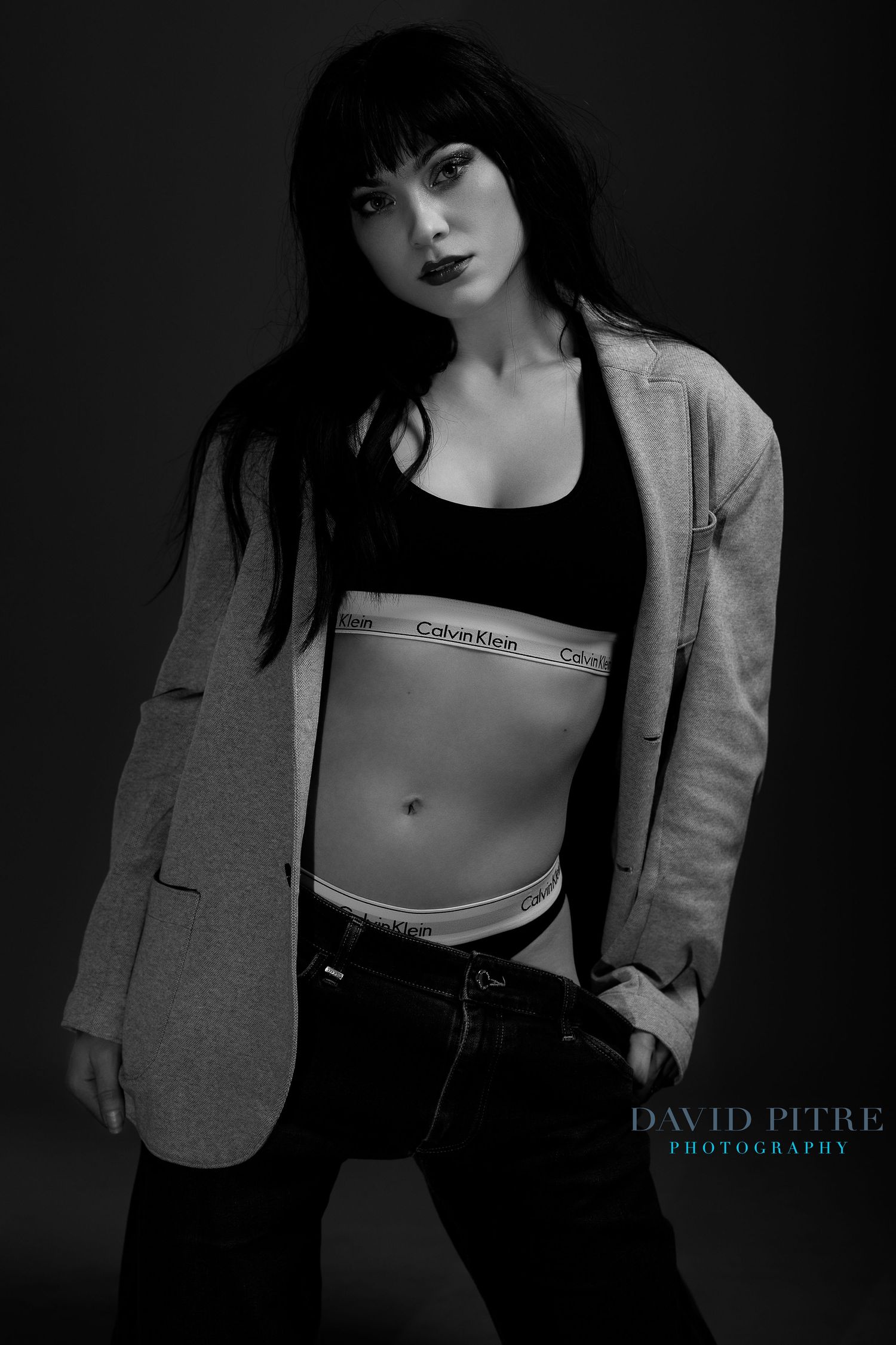 Moody fashion photography featuring grey blazer and Calvin Klein sportswear in studio lighting.