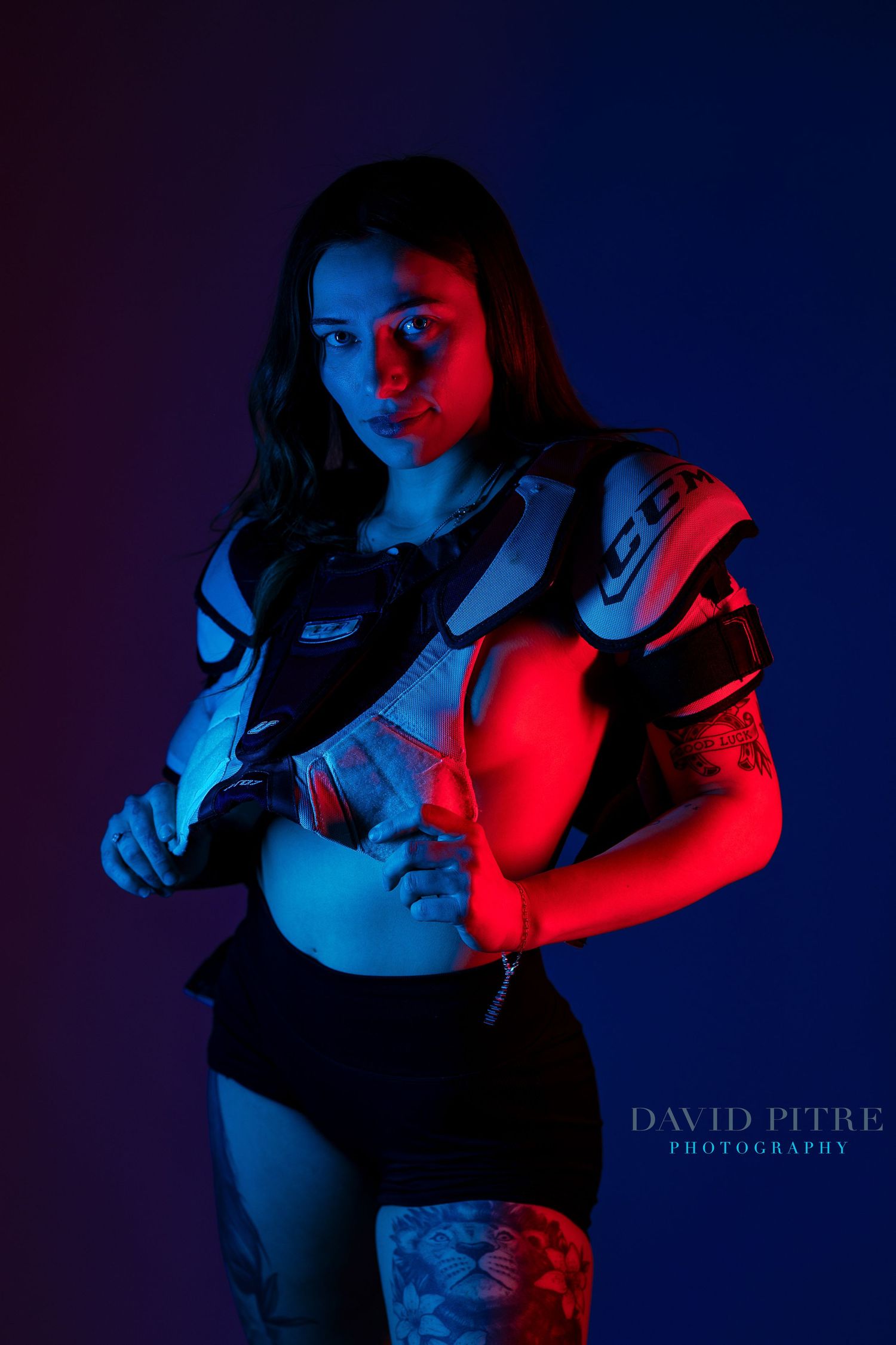 Dramatic portrait with red and blue lighting creating moody shadows and silhouettes against dark background.