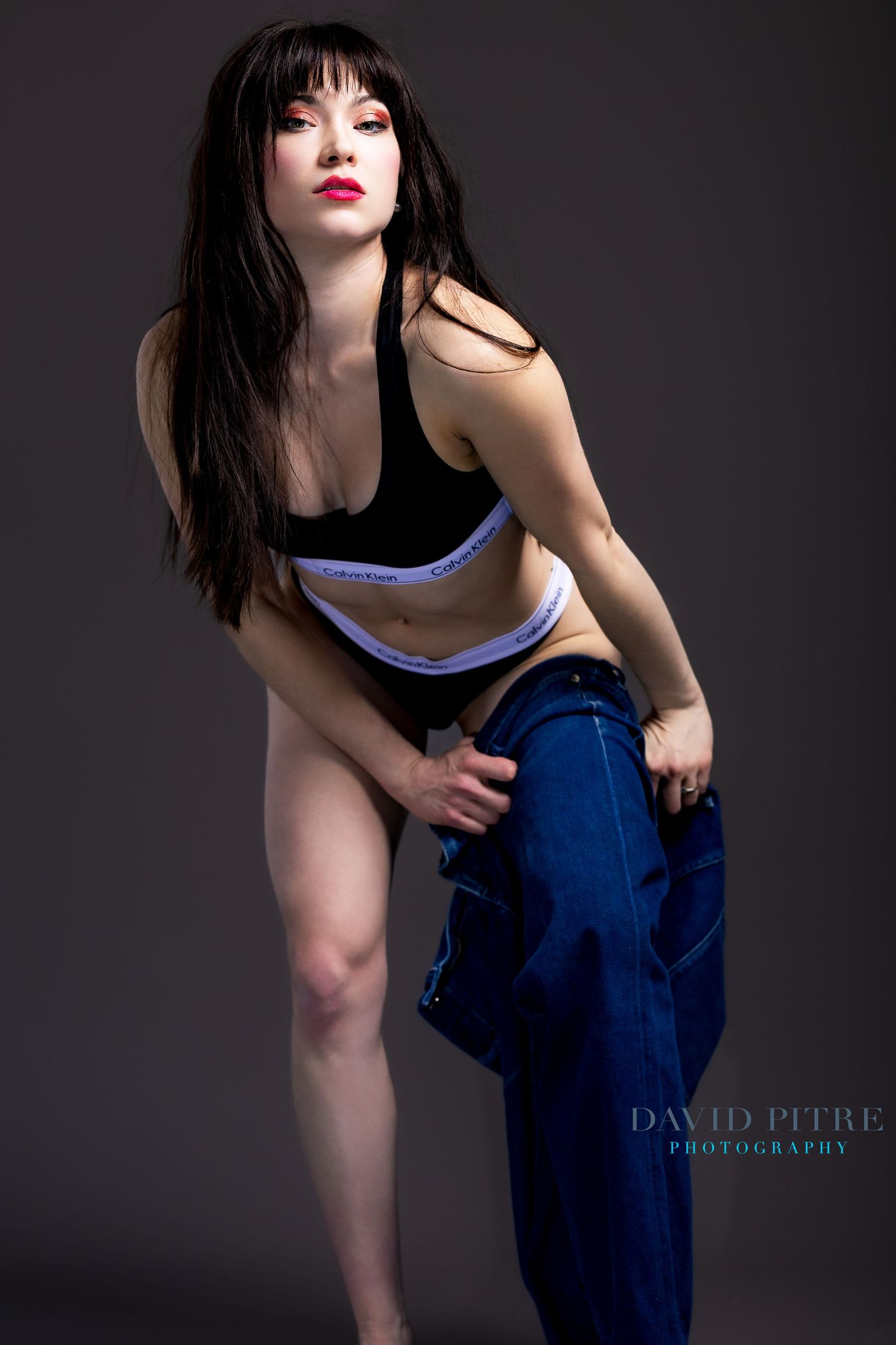 Artistic fashion photo series showing model in blue jeans and white top against dark background with dramatic lighting.