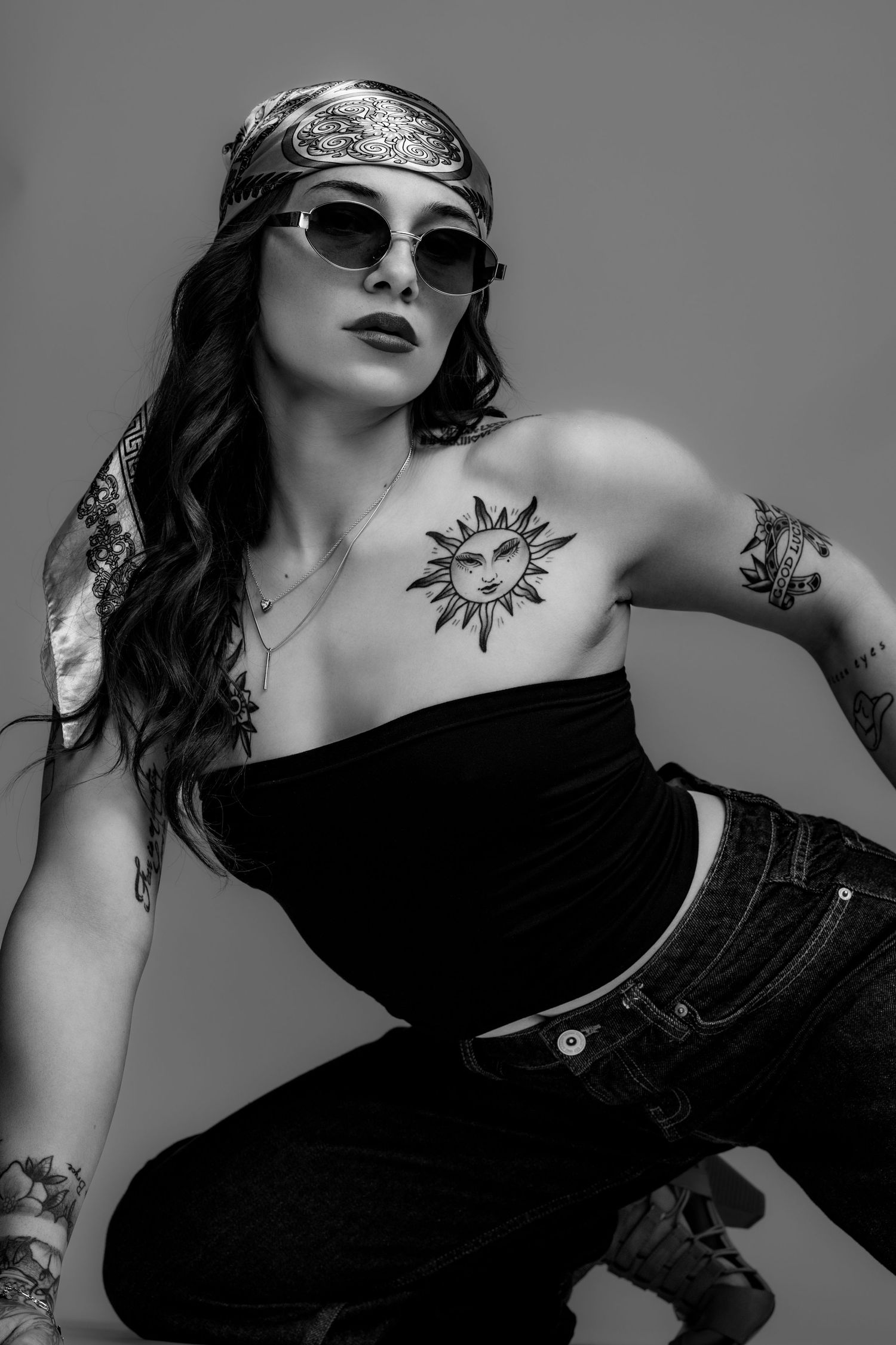 Artistic black and white photo series showing a sun tattoo and sunglasses in dramatic poses with dark clothing.