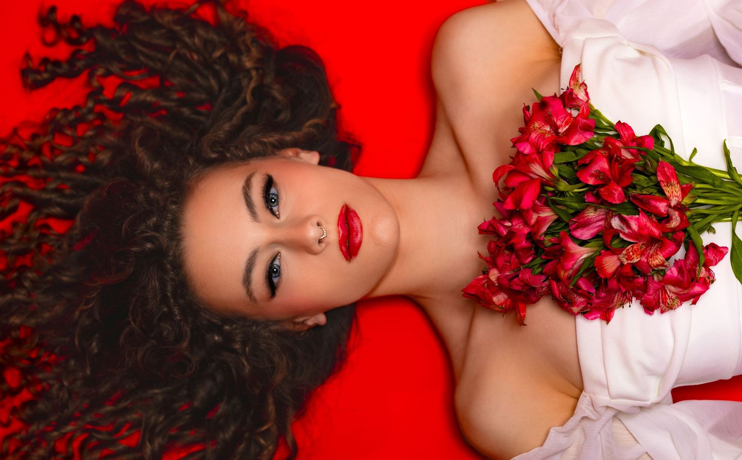 Artistic portrait series on red background with roses and white fabric creating romantic Valentine's Day themed composition.