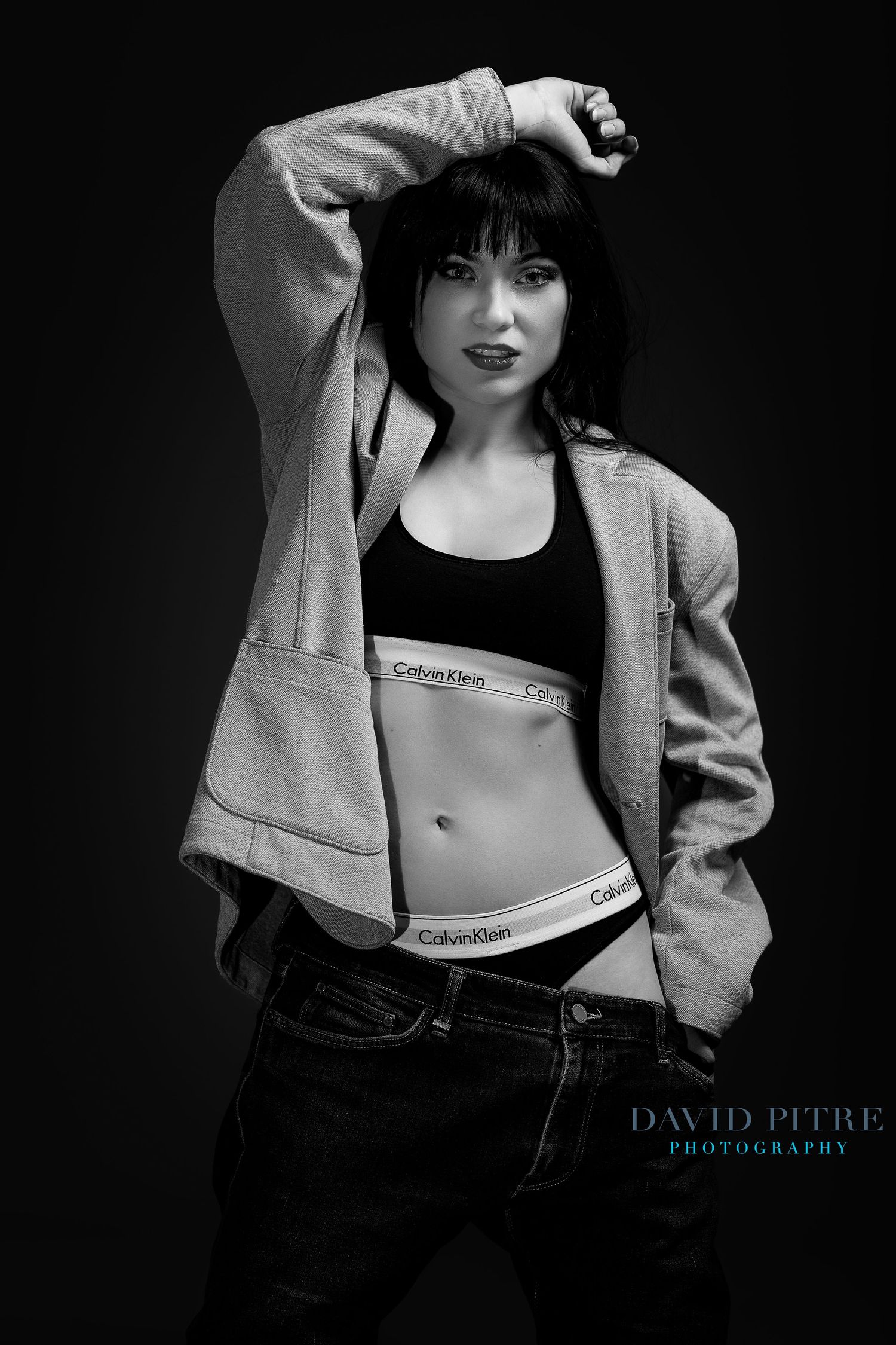 Black and white fashion photo series showing a model in Calvin Klein sportswear and an oversized jacket against dark background.
