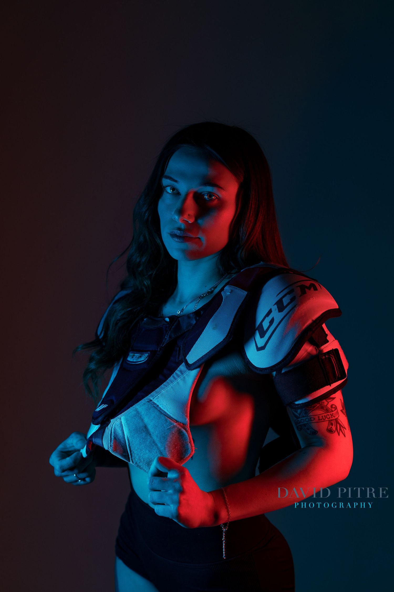 Dramatic portrait with neon blue and red lighting creating a cyberpunk aesthetic in dark studio setting.