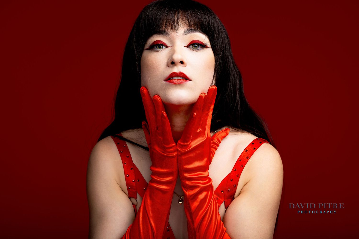 A dramatic fashion portrait series with red gloves and black hair against a deep red background.