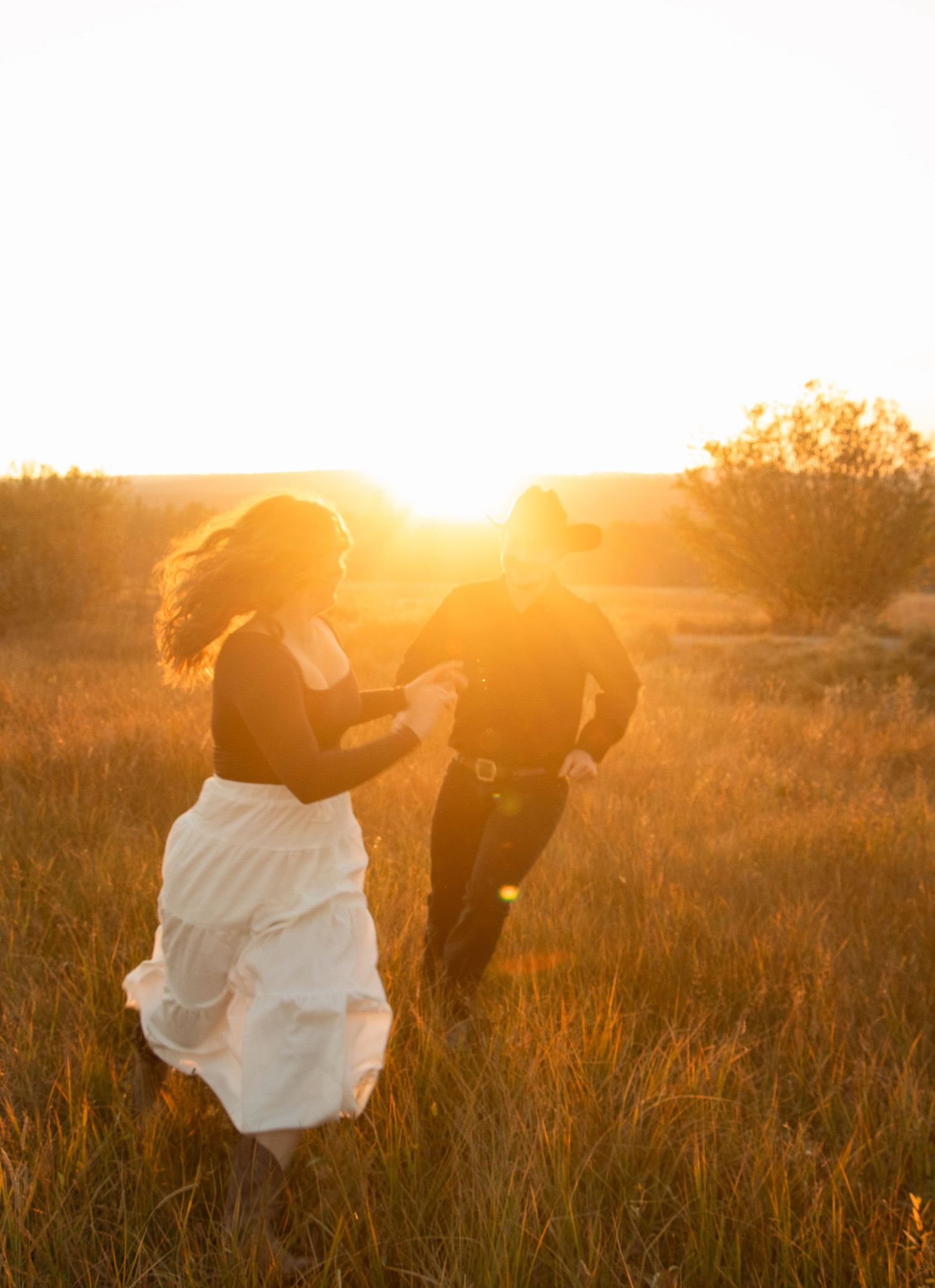a couple runs through a field at Dillon Falls in Oregon as the golden sun shines on them