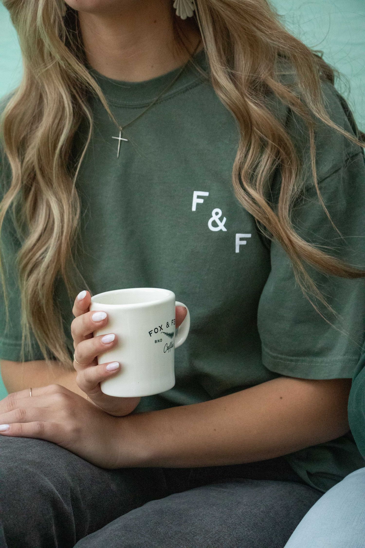 a young woman holds a cup of coffee at a Bend, Oregon coffee shop