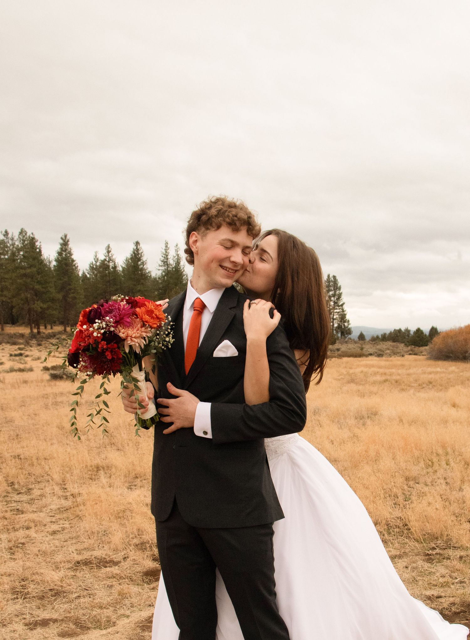 a bride and groom stand together in a grassy field in Sisters, Oregon