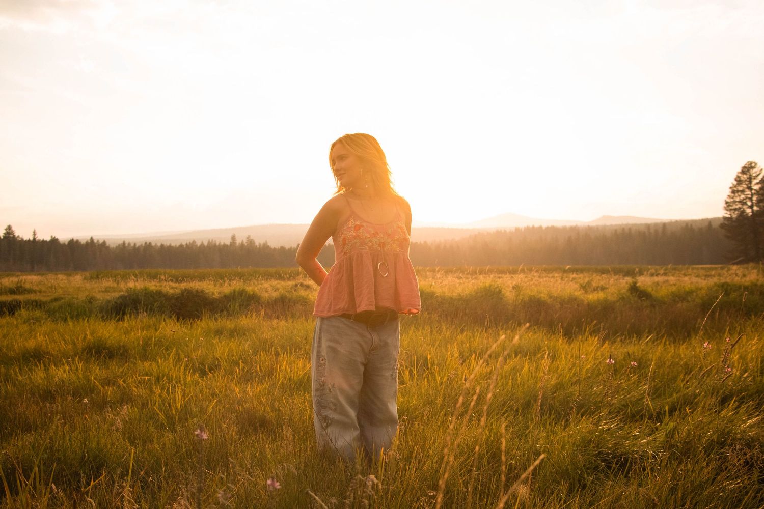 a young woman stands in the flowing grass at a park in Bend, Oregon