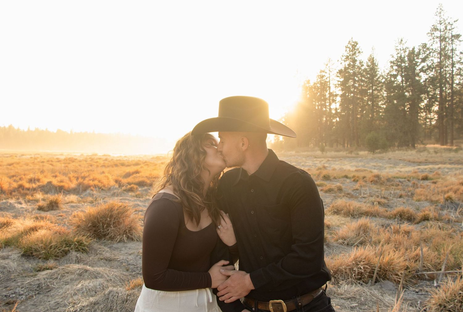 a couple leans in for a kiss lit up by the Central Oregon sun