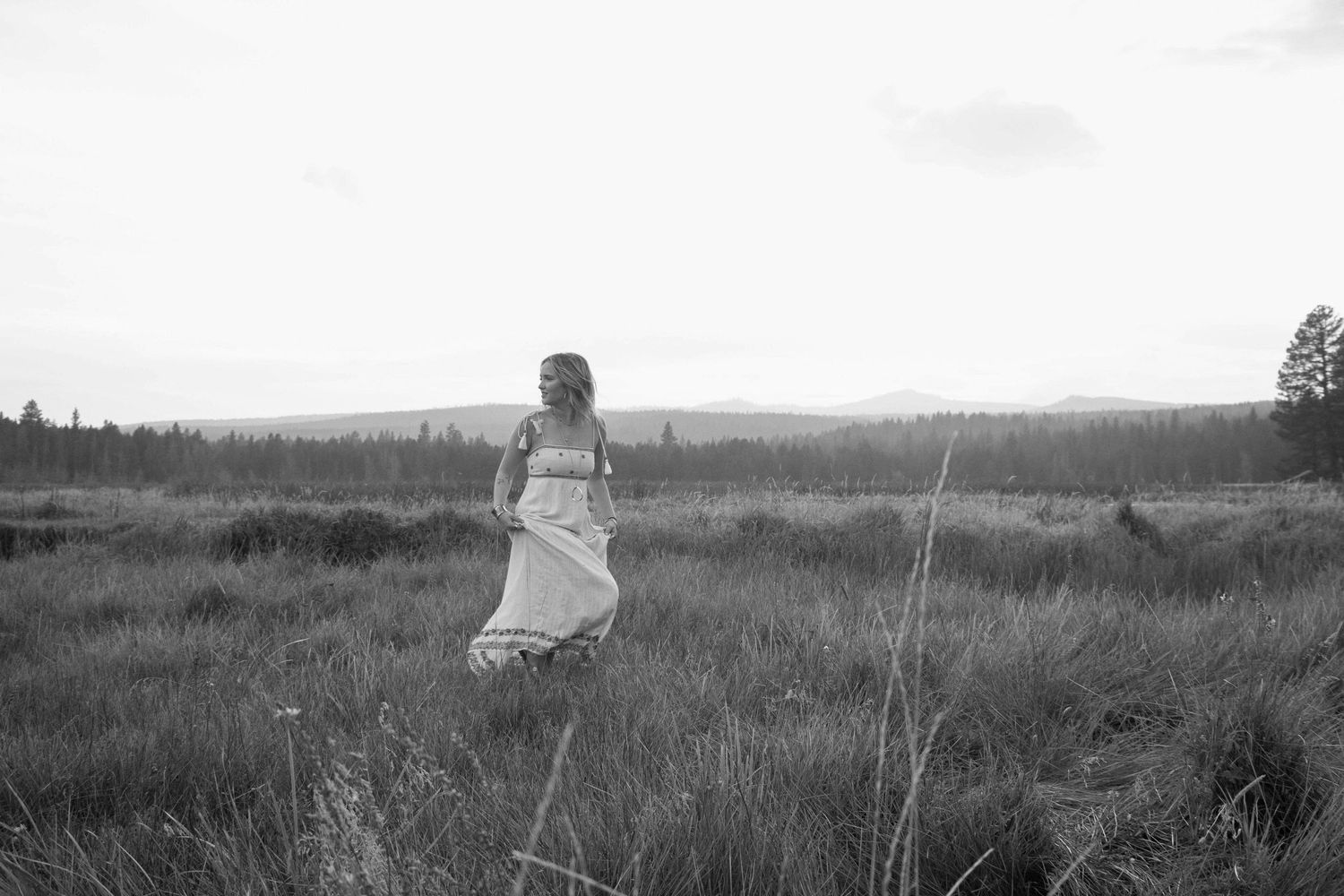 a young woman walks across a wide open Oregon mountain field