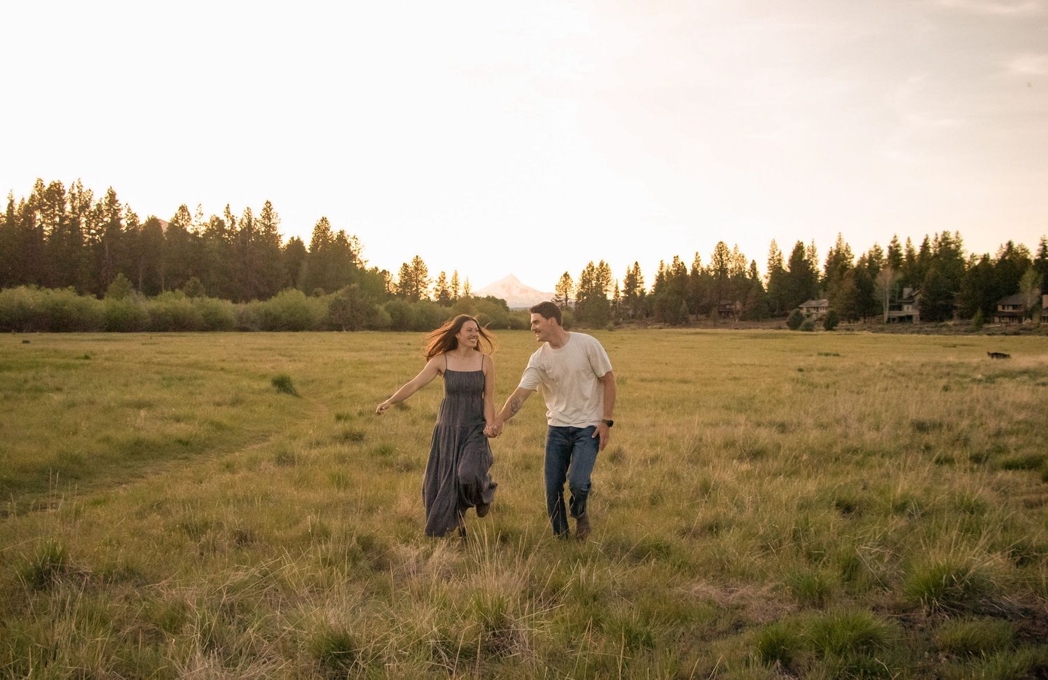 a couple runs through a wide, grassy field in Sisters, Oregon