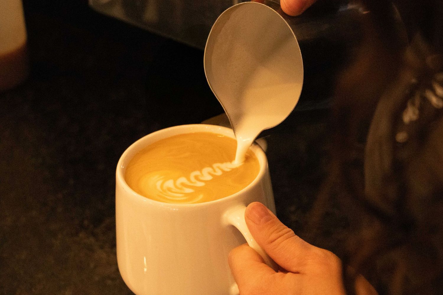 a barista at a Bend, Oregon coffee shop pours milk into a coffee drink
