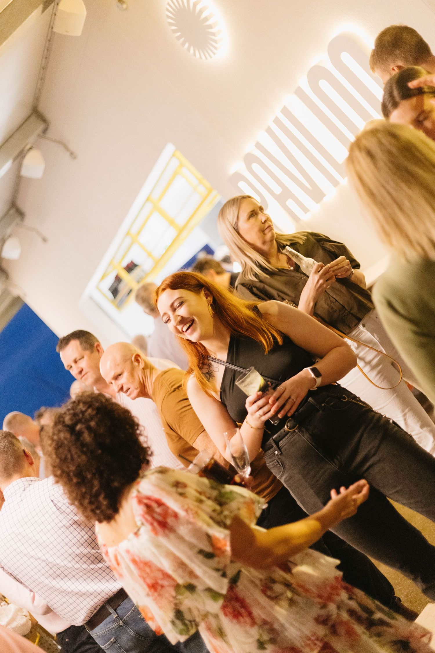 People socializing at an indoor event with bright lighting and modern decor.