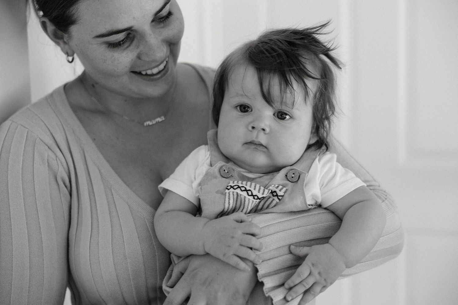 Parent and baby sharing affectionate moments against white backdrop.