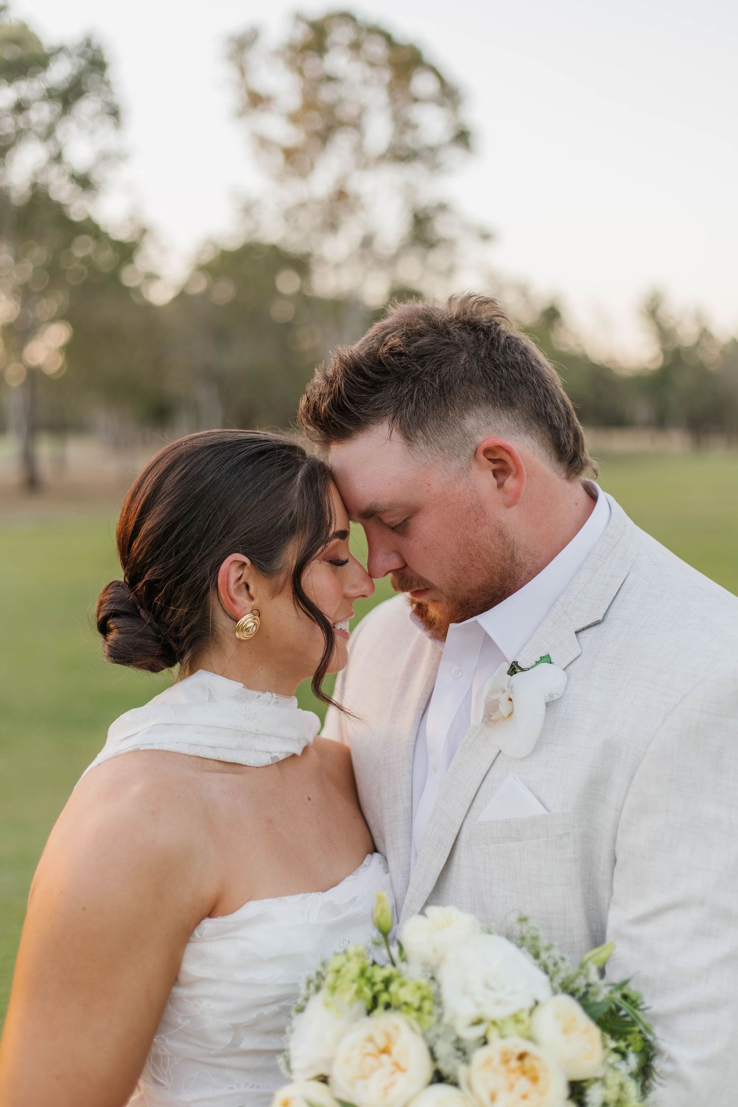 Intimate moment between newlyweds sharing a tender embrace outdoors.