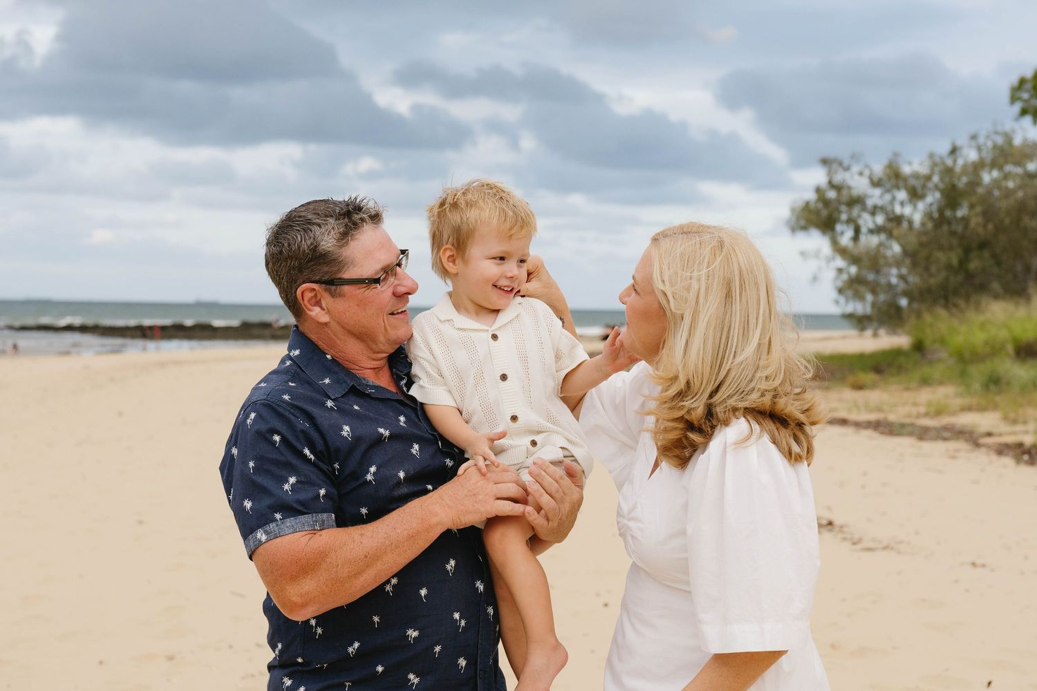 Family shares tender moments together during a beach photoshoot at sunset.