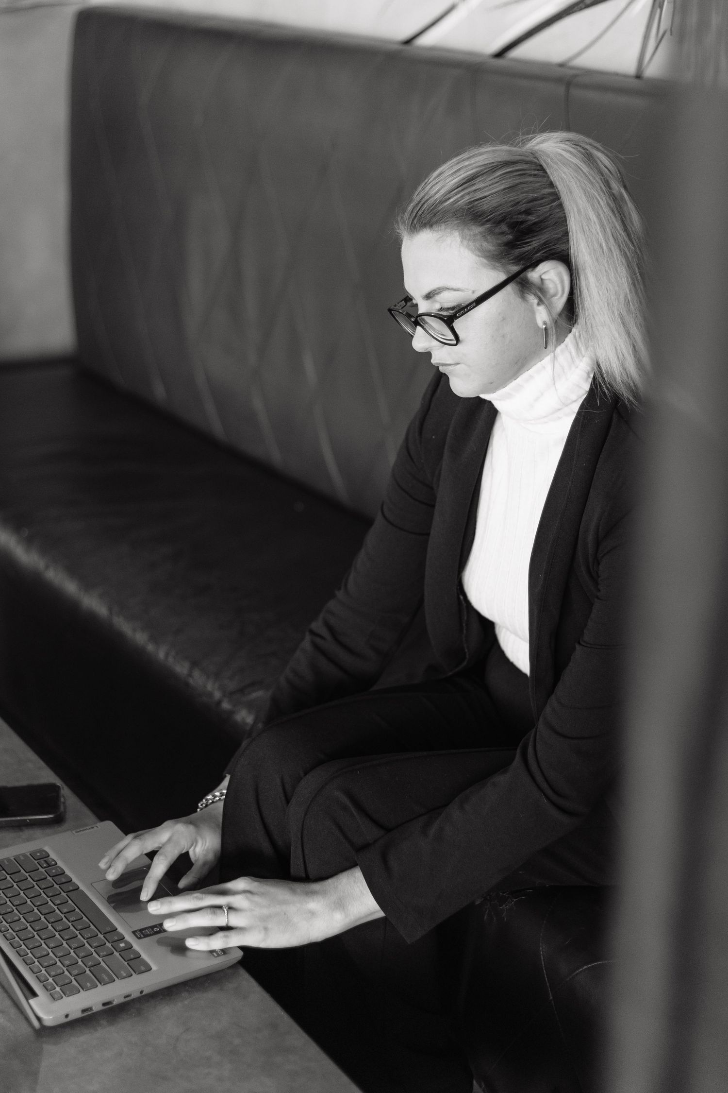 Person in business attire working on laptop and mobile devices in office setting.