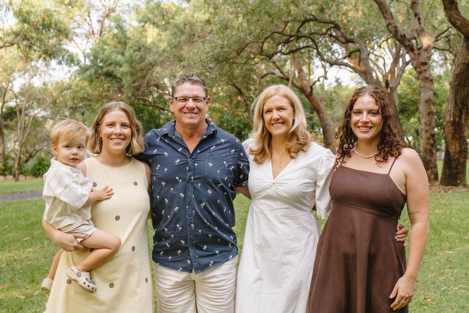 Extended family gathering outdoors in coordinated neutral-toned outfits.