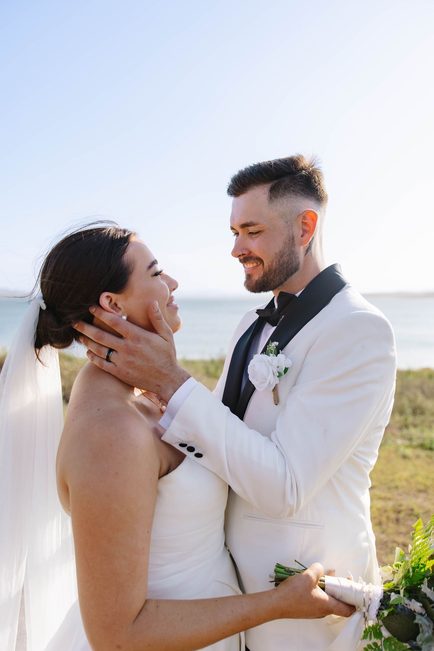 Romantic wedding moment captured against a bright sky backdrop.