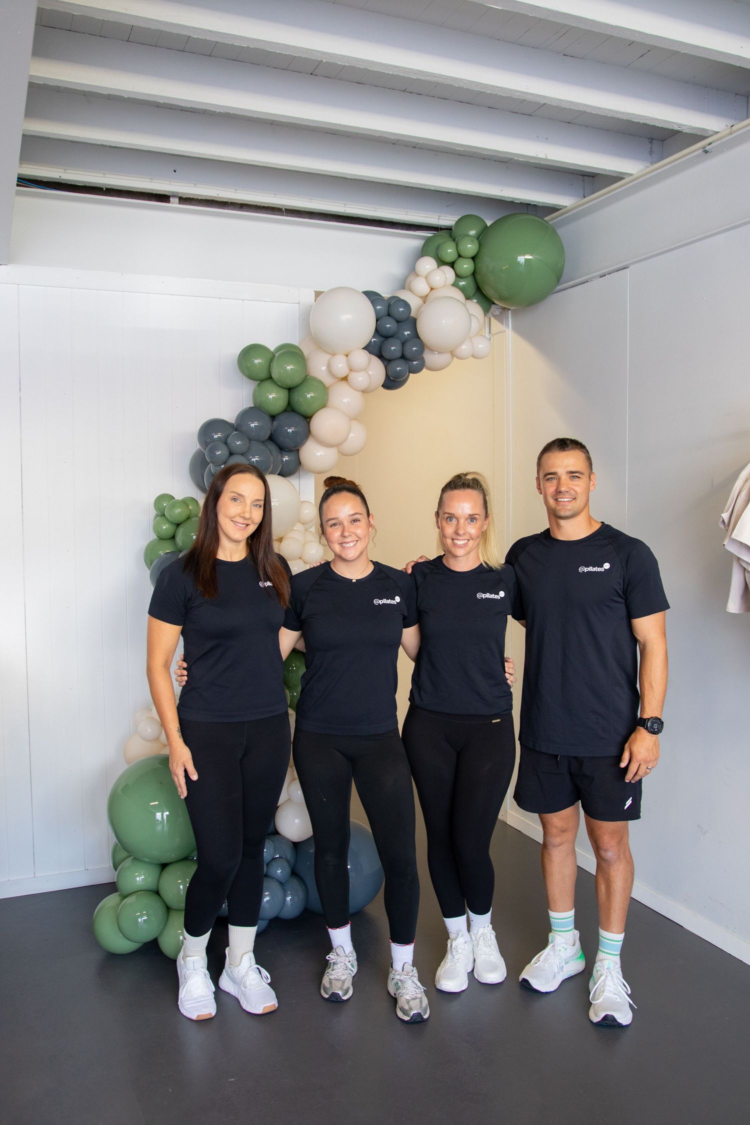 Team members in matching black uniforms standing together with balloon decorations.
