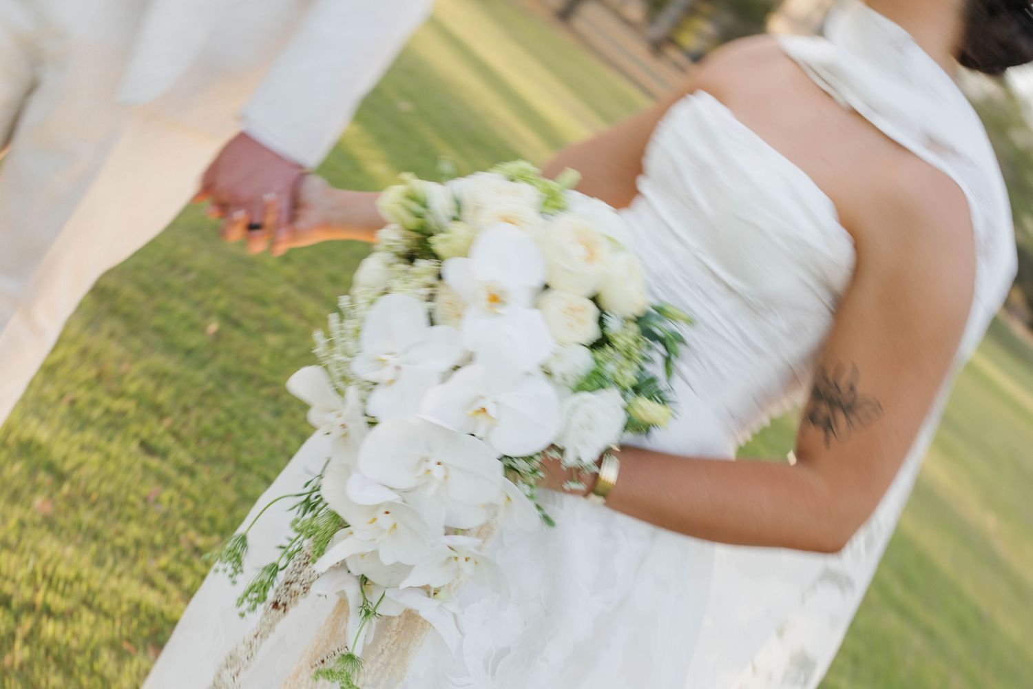 Close-up of an elegant white orchid wedding bouquet against a bridal gown.