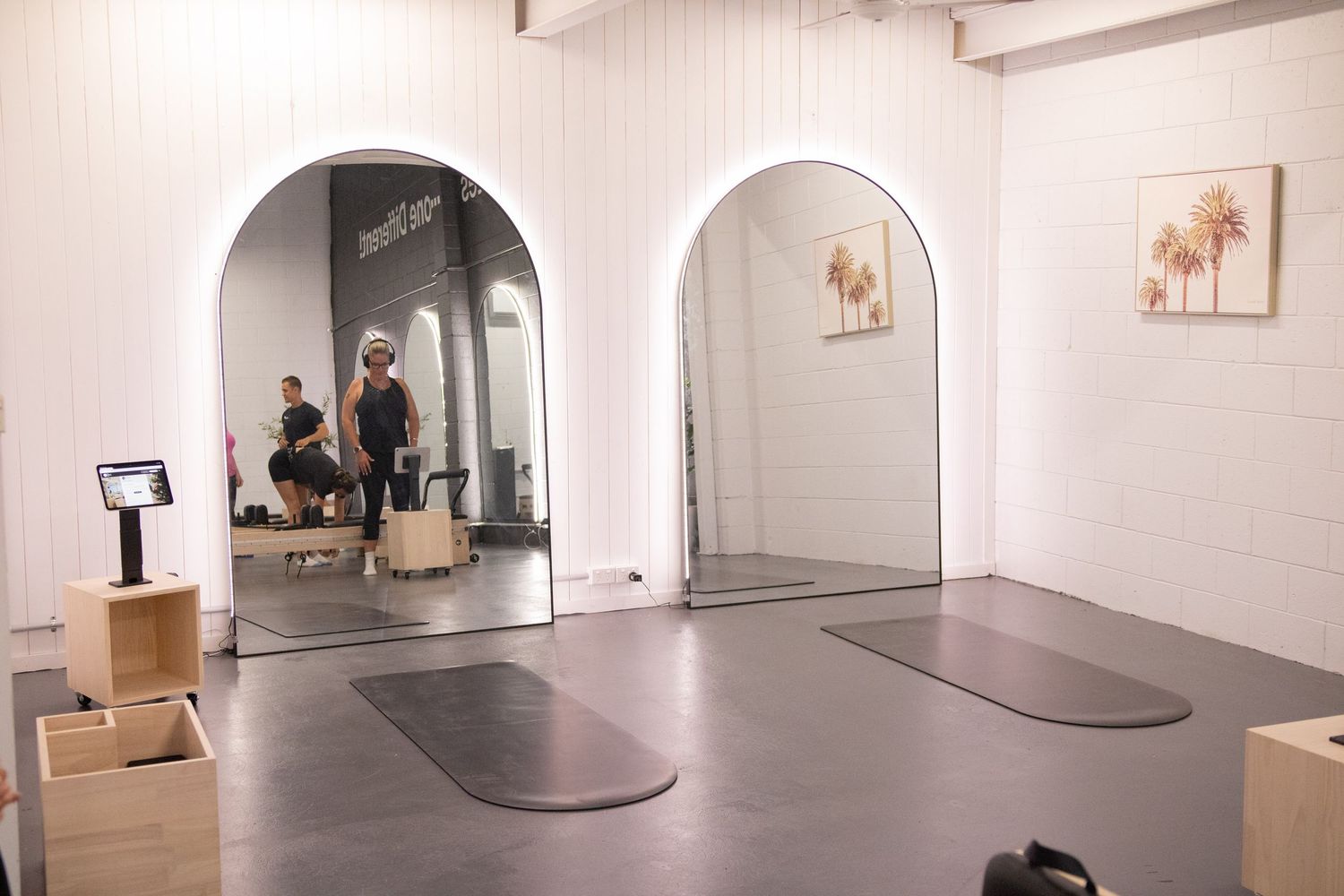 Clean white pilates studio interior with reformer equipment and arched doorways.