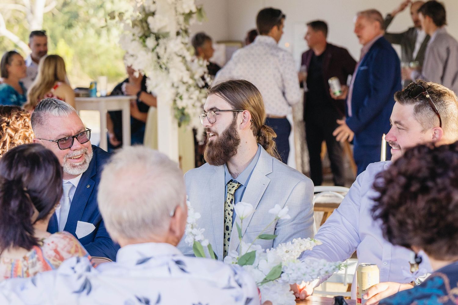 Wedding guests gathered at reception tables during daytime celebration.