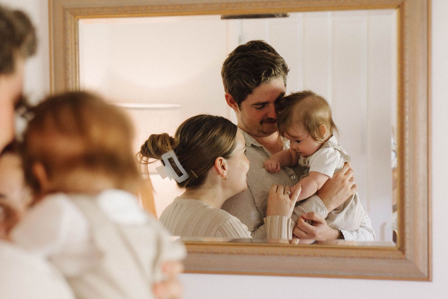Intimate family reflections shown through a series of mirror frames on a wall.