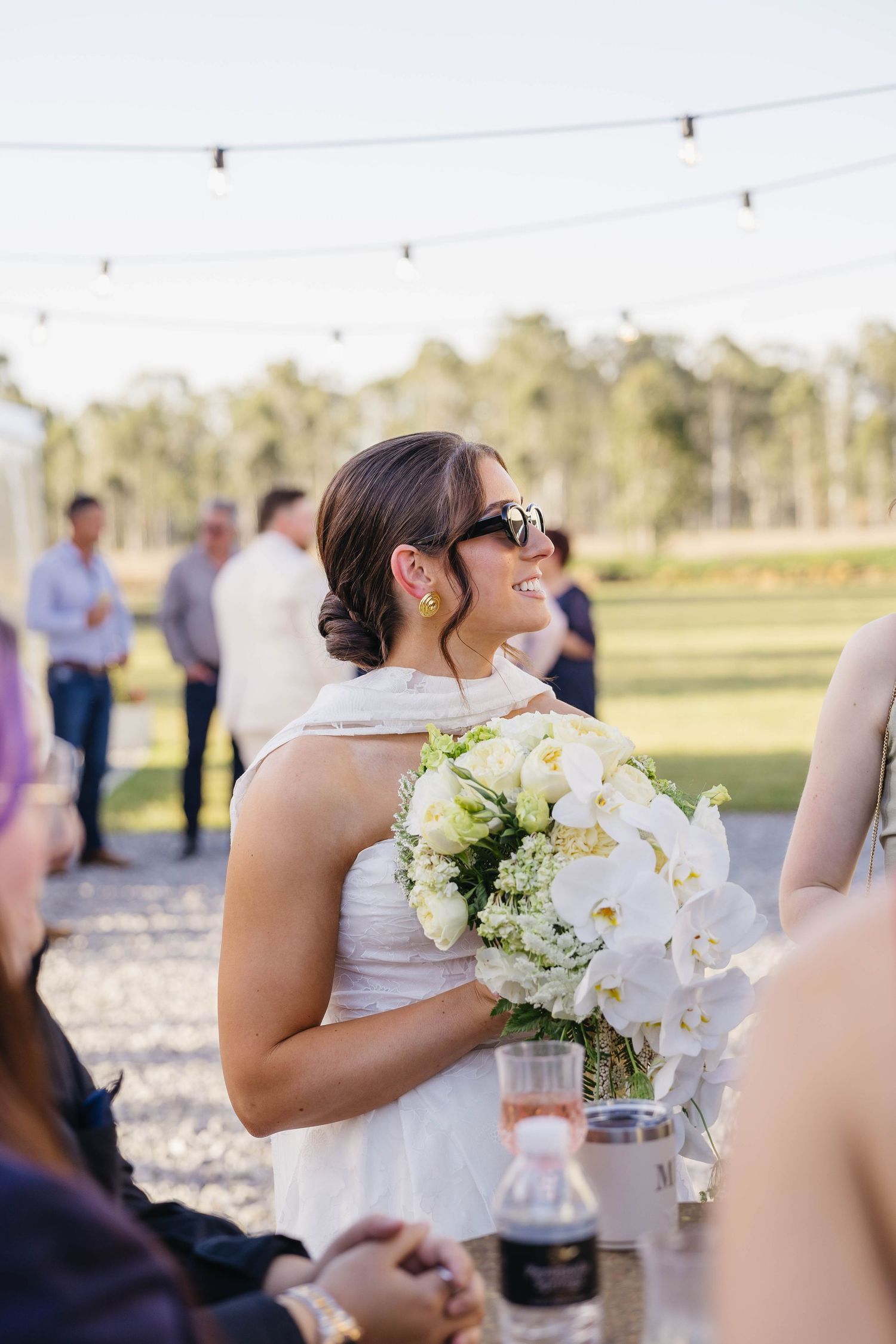 Elegant outdoor wedding reception setup with string lights and white floral arrangements.