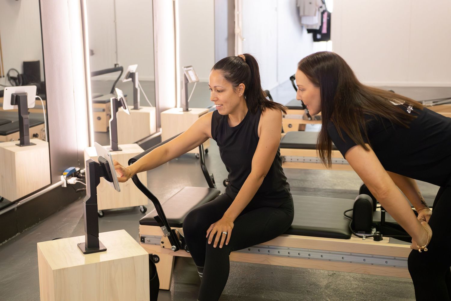 Students practicing exercises on pilates reformer machines in studio.