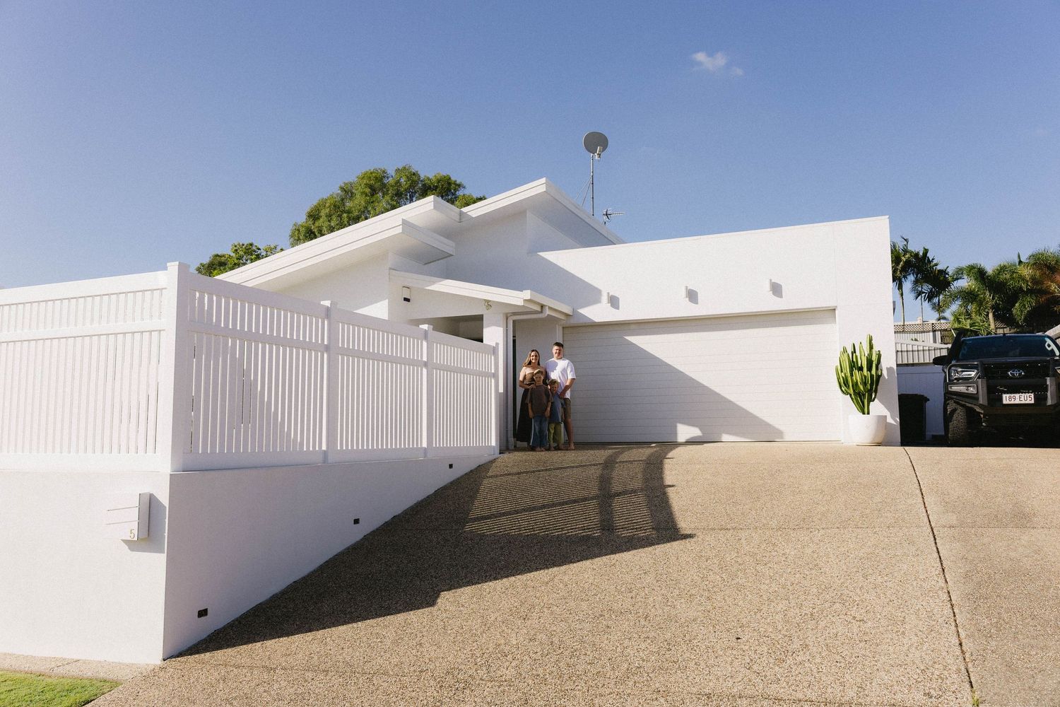 Modern white exterior wall with geometric shadows creating diagonal lines.