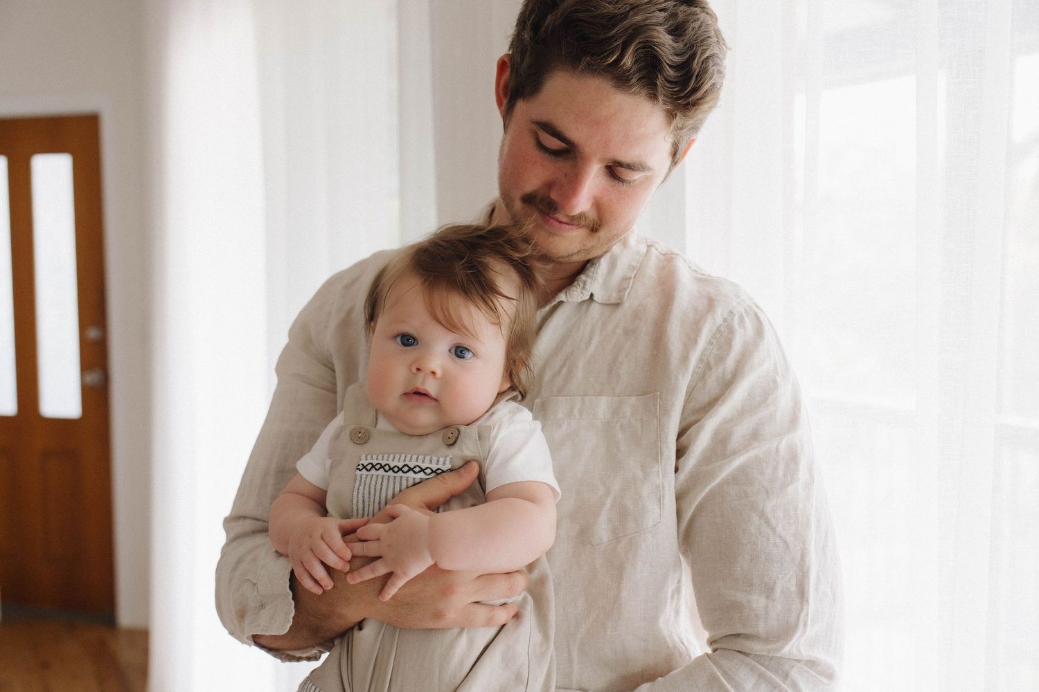 Tender family moment captured in a bright white interior setting.