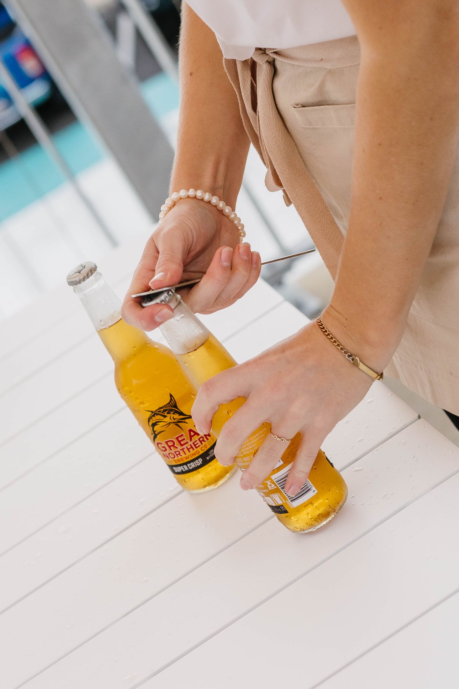 Hands placing yellow drink coasters on white wooden surface.