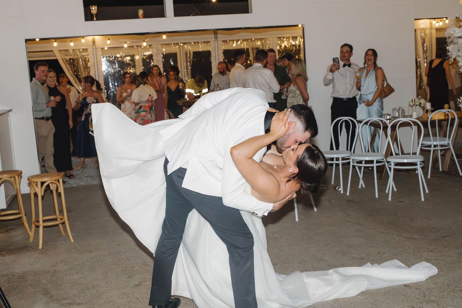 A dramatic wedding dance dip captured during the reception in a white indoor venue.