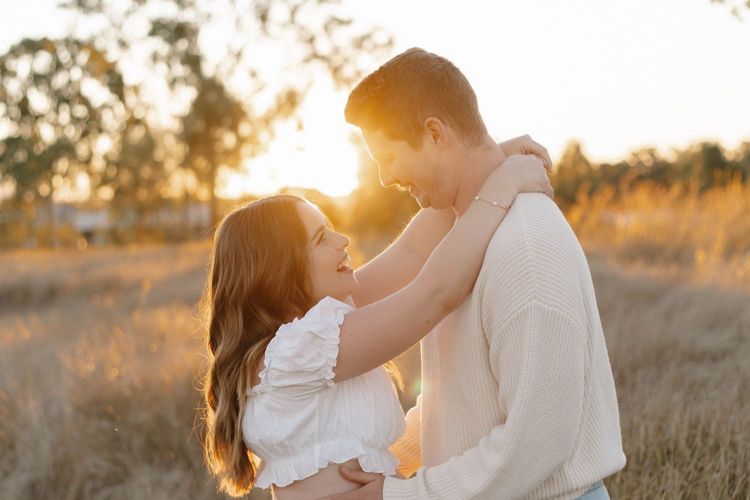 Romantic couple photoshoot in a field during golden hour sunset.