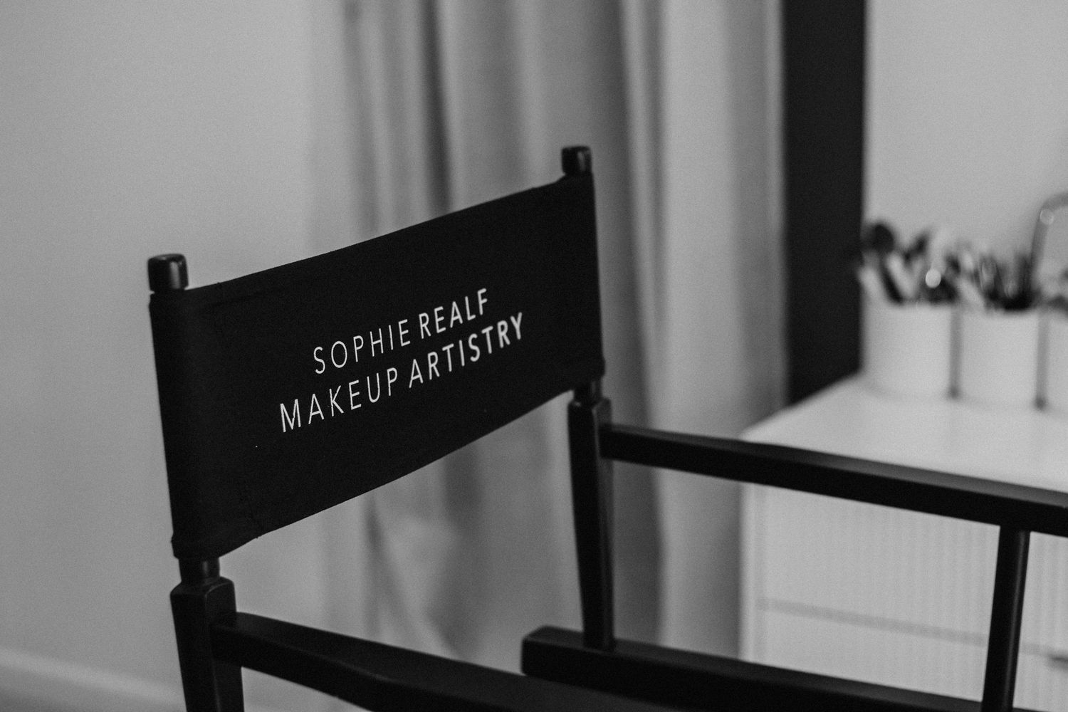 Row of black director-style chairs with text on the backs in a studio setting.