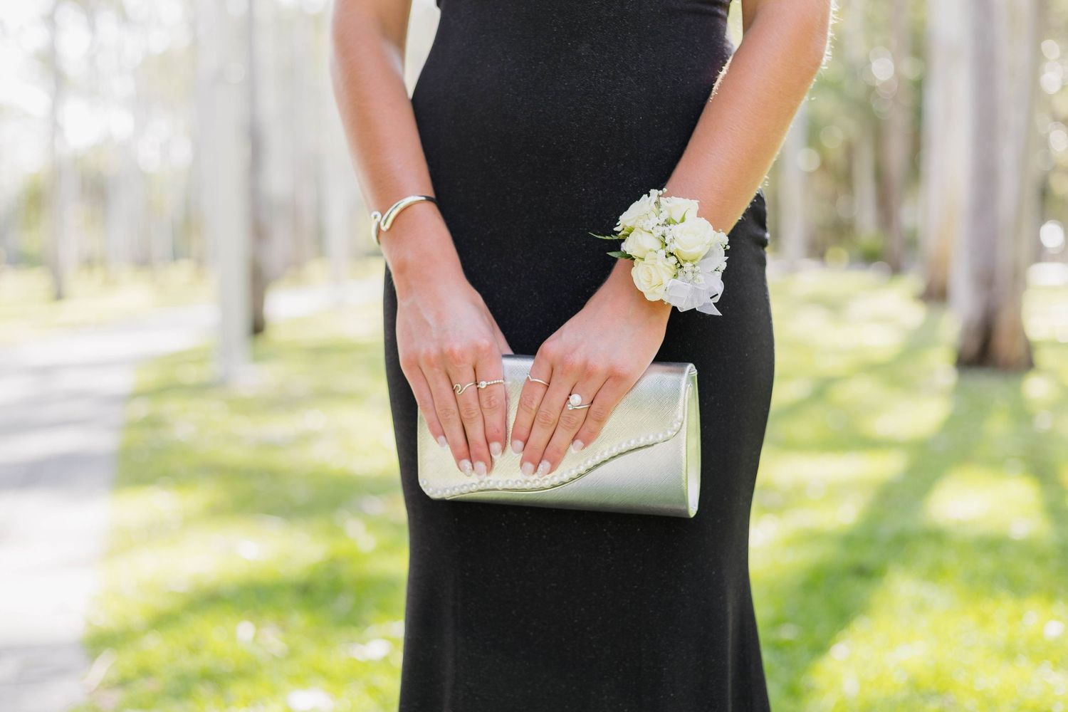 Hands holding a white floral corsage against formal black attire.