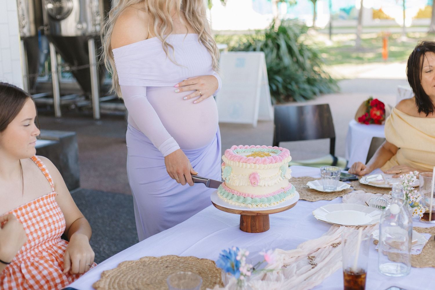 People gather around a table at a baby shower celebration with cake and refreshments.