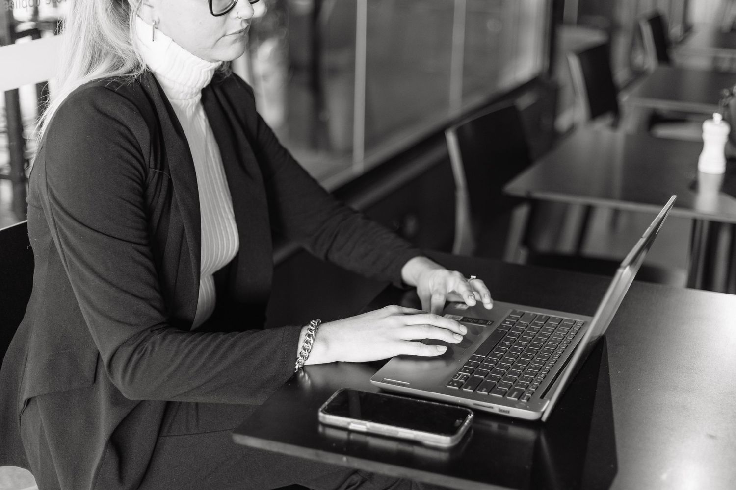 Professional working on laptop and mobile devices at modern workspace.