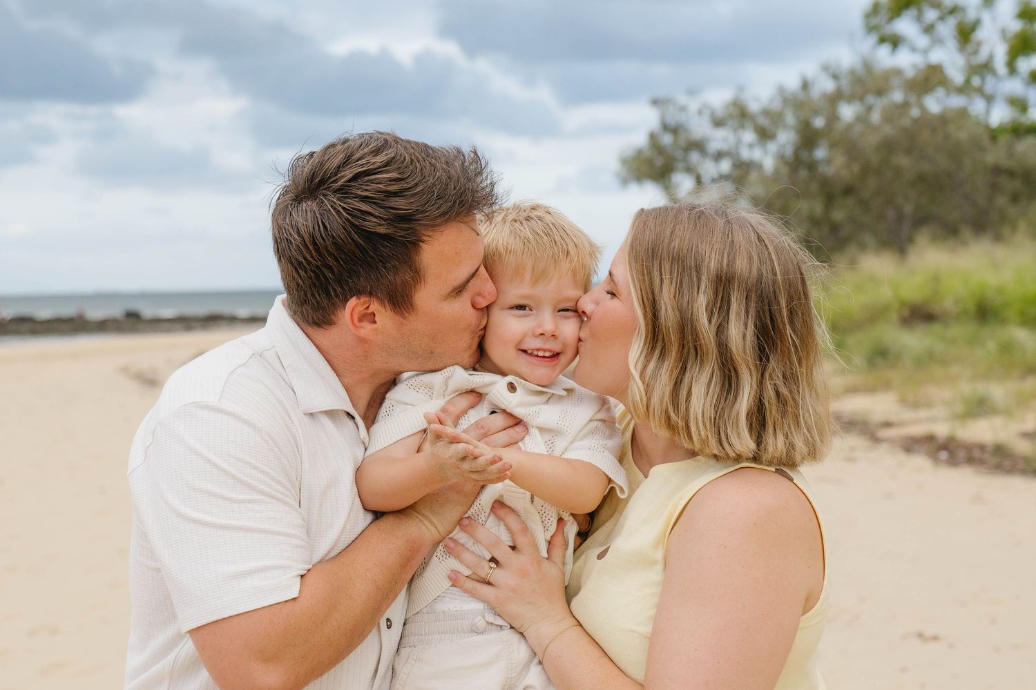 Intimate family portrait session with loving embraces on a sandy beach.