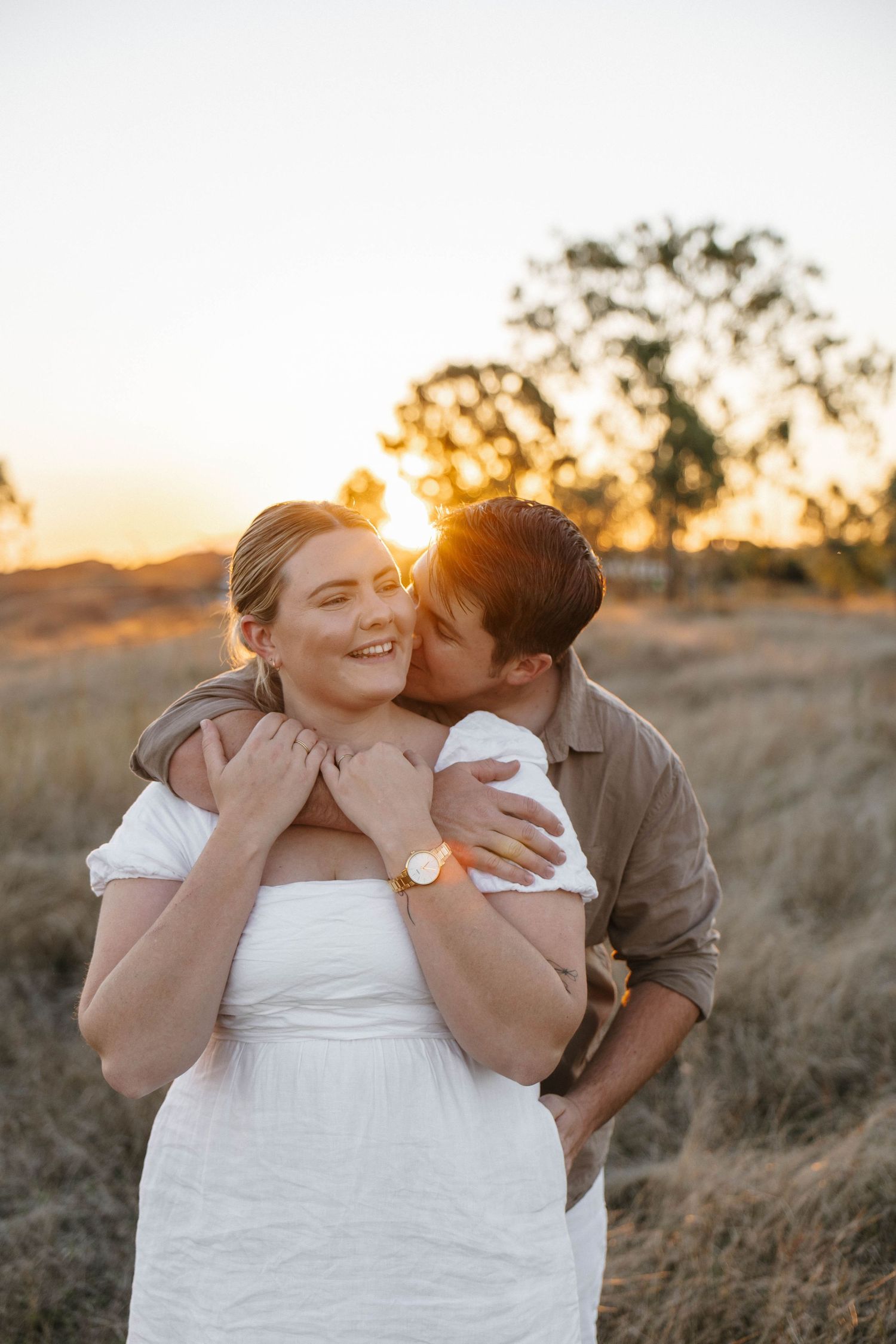 Romantic sunset photoshoot in a field with warm golden lighting.