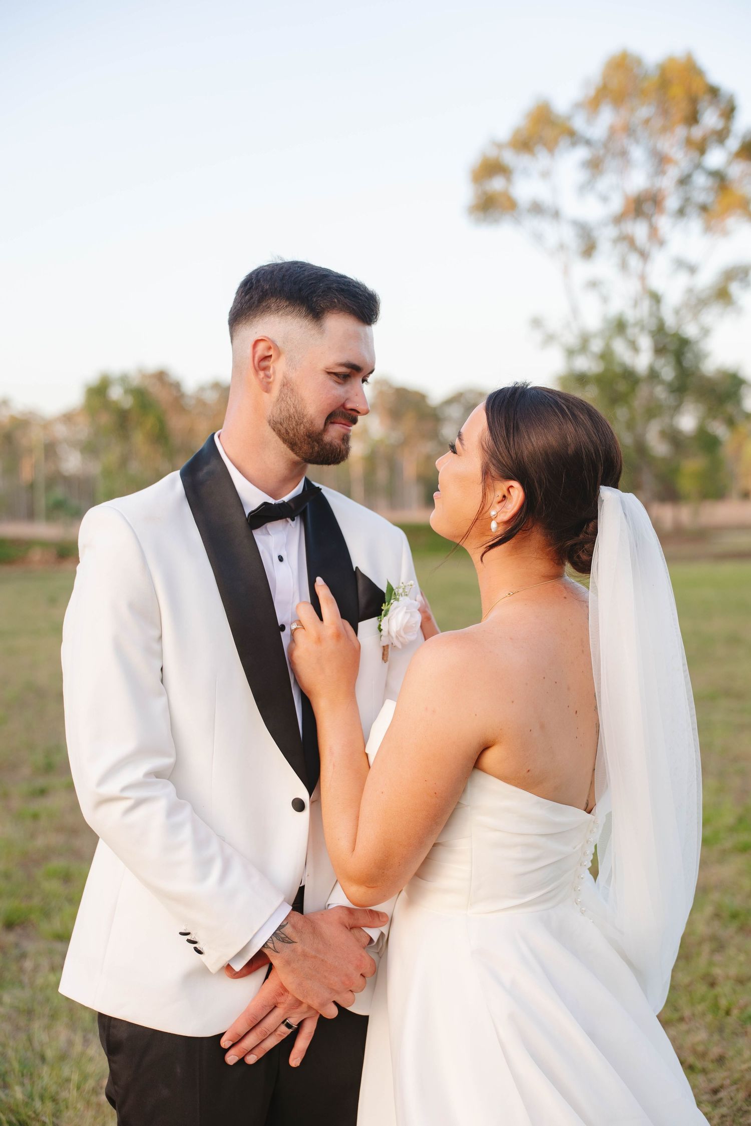 A wedding couple shares an intimate moment against a rustic outdoor backdrop.